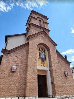 главни улаз у храм са каменим порталом и мозаиком заштитника изнад врата