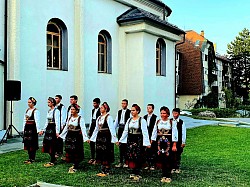верни народ и омладина у народним ношњама играју коло испред храма светог архангела гаврила
