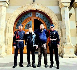 На фотографији испред главног портала Храма Преображења Господњег на Златибору стоје четворица мушкараца. Са леве и десне стране налазе се двојица припадника Посебне јединице полиције (ПЈП) у свечаним тамноплавим униформама са карактеристичним плавим береткама и црвеним акселбендерима. Између њих, у знак заједништва и поштовања према страдалима, стоје двојица мушкараца у цивилној одећи. Изнад њихових глава доминира камени лук улаза у златиборску светињу са натписима на црквенословенском језику. Слика одише поносом и војничком чашћу уочи одржавања помена херојима који су положили живот за отаџбину